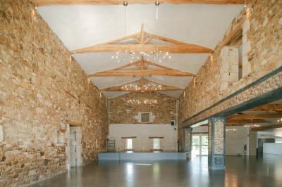 Chemin de gravier menant à une maison en pierre avec toit en tuiles, entourée de verdure et d'une clôture en bois.