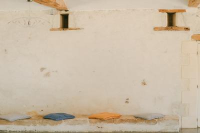 Chemin de gravier menant à une maison en pierre avec toit en tuiles, entourée de verdure et d'une clôture en bois.