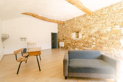 Chemin de gravier menant à une maison en pierre avec toit en tuiles, entourée de verdure et d'une clôture en bois.