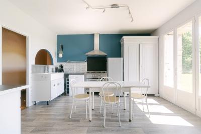 Chemin de gravier menant à une maison en pierre avec toit en tuiles, entourée de verdure et d'une clôture en bois.