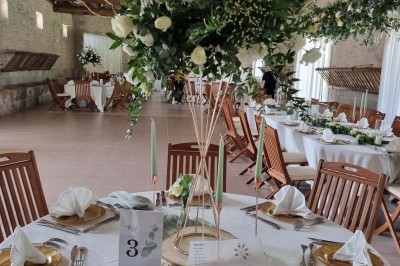 Chaises blanches disposées en rangées sur une pelouse, face à une petite scène décorée pour un événement en plein air.