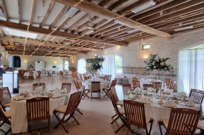 Chaises blanches disposées en rangées sur une pelouse, face à une petite scène décorée pour un événement en plein air.