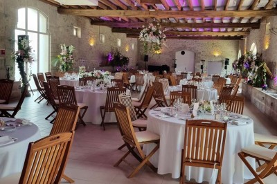 Chaises blanches disposées en rangées sur une pelouse, face à une petite scène décorée pour un événement en plein air.