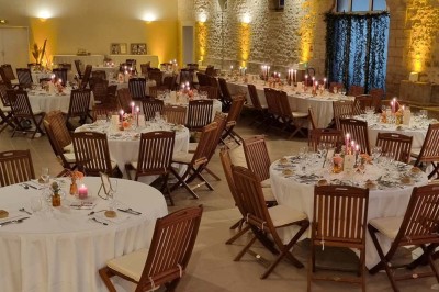 Chaises blanches disposées en rangées sur une pelouse, face à une petite scène décorée pour un événement en plein air.