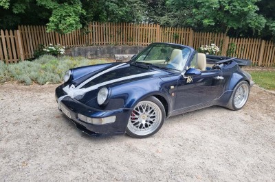 Chaises blanches disposées en rangées sur une pelouse, face à une petite scène décorée pour un événement en plein air.