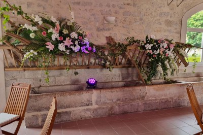 Chaises blanches disposées en rangées sur une pelouse, face à une petite scène décorée pour un événement en plein air.