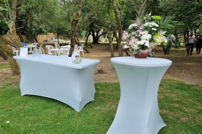Chaises blanches disposées en rangées sur une pelouse, face à une petite scène décorée pour un événement en plein air.