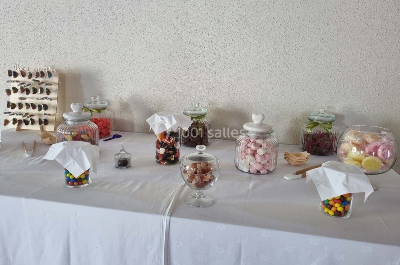 Table avec des bonbonnières remplies de bonbons colorés et variés, disposées pour un buffet ou une réception.