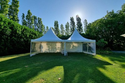 Chaises blanches disposées en rangées sur une pelouse, face à une petite scène décorée pour un événement en plein air.