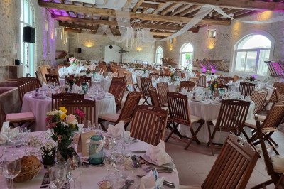 Chaises blanches disposées en rangées sur une pelouse, face à une petite scène décorée pour un événement en plein air.