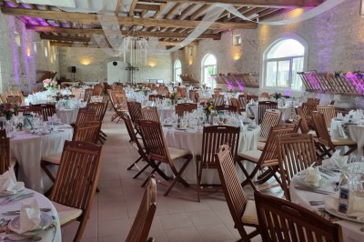 Chaises blanches disposées en rangées sur une pelouse, face à une petite scène décorée pour un événement en plein air.