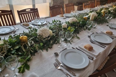 Chaises blanches disposées en rangées sur une pelouse, face à une petite scène décorée pour un événement en plein air.