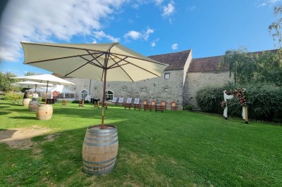 Chaises blanches disposées en rangées sur une pelouse, face à une petite scène décorée pour un événement en plein air.