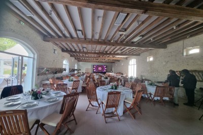 Chaises blanches disposées en rangées sur une pelouse, face à une petite scène décorée pour un événement en plein air.