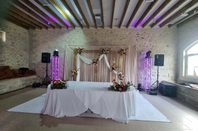 Chaises blanches disposées en rangées sur une pelouse, face à une petite scène décorée pour un événement en plein air.