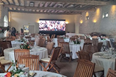 Chaises blanches disposées en rangées sur une pelouse, face à une petite scène décorée pour un événement en plein air.