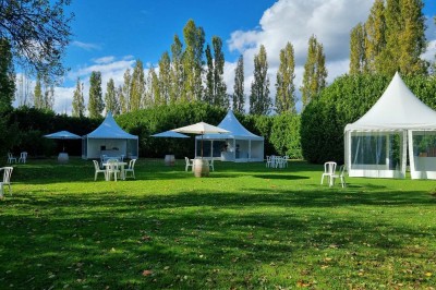 Chaises blanches disposées en rangées sur une pelouse, face à une petite scène décorée pour un événement en plein air.