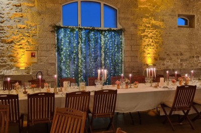 Chaises blanches disposées en rangées sur une pelouse, face à une petite scène décorée pour un événement en plein air.