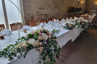 Chaises blanches disposées en rangées sur une pelouse, face à une petite scène décorée pour un événement en plein air.
