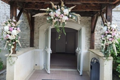 Chaises blanches disposées en rangées sur une pelouse, face à une petite scène décorée pour un événement en plein air.