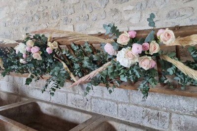 Chaises blanches disposées en rangées sur une pelouse, face à une petite scène décorée pour un événement en plein air.