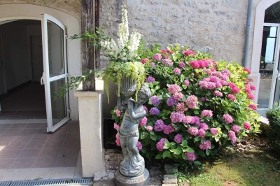 Chaises blanches disposées en rangées sur une pelouse, face à une petite scène décorée pour un événement en plein air.