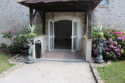 Chaises blanches disposées en rangées sur une pelouse, face à une petite scène décorée pour un événement en plein air.