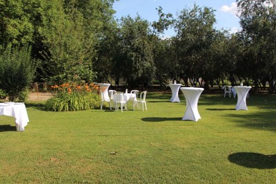 Chaises blanches disposées en rangées sur une pelouse, face à une petite scène décorée pour un événement en plein air.