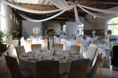 Chaises blanches disposées en rangées sur une pelouse, face à une petite scène décorée pour un événement en plein air.