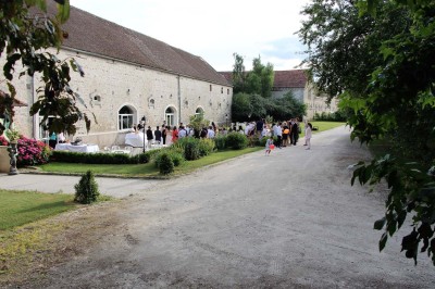 Chaises blanches disposées en rangées sur une pelouse, face à une petite scène décorée pour un événement en plein air.