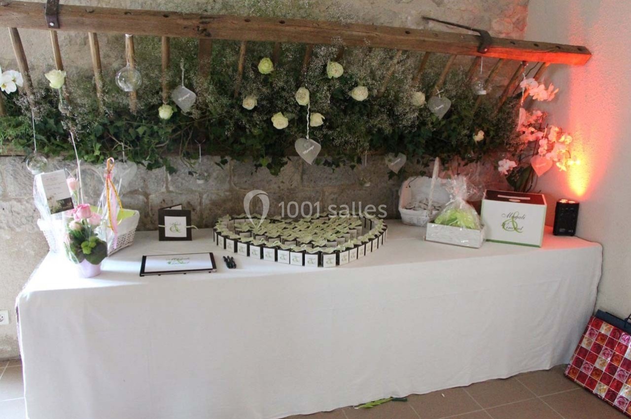 Table décorée avec des cadeaux, des fleurs et des friandises, disposée dans un cadre rustique avec un mur en pierre.