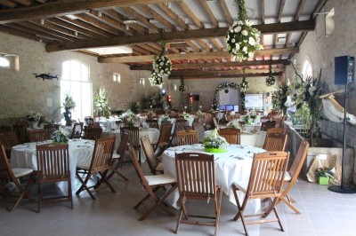 Chaises blanches disposées en rangées sur une pelouse, face à une petite scène décorée pour un événement en plein air.