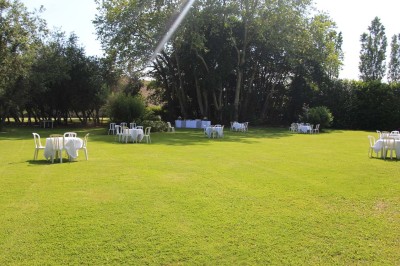 Chaises blanches disposées en rangées sur une pelouse, face à une petite scène décorée pour un événement en plein air.