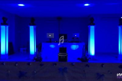 Installation de matériel DJ avec éclairage bleu, comprenant des colonnes lumineuses et des équipements audio.