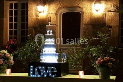 Terrasse en bois avec des chaises noires, adossée à une maison en bardage bois, sous un ciel nuageux.