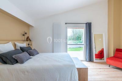 Terrasse en bois avec des chaises noires, adossée à une maison en bardage bois, sous un ciel nuageux.