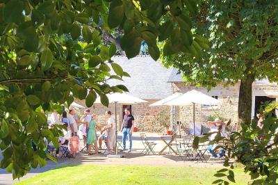 Terrasse en bois avec des chaises noires, adossée à une maison en bardage bois, sous un ciel nuageux.