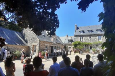 Terrasse en bois avec des chaises noires, adossée à une maison en bardage bois, sous un ciel nuageux.