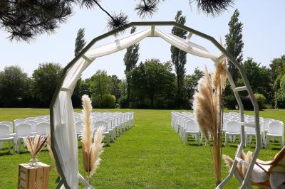 Terrasse en bois avec des chaises noires, adossée à une maison en bardage bois, sous un ciel nuageux.