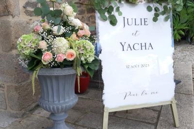 Terrasse en bois avec des chaises noires, adossée à une maison en bardage bois, sous un ciel nuageux.
