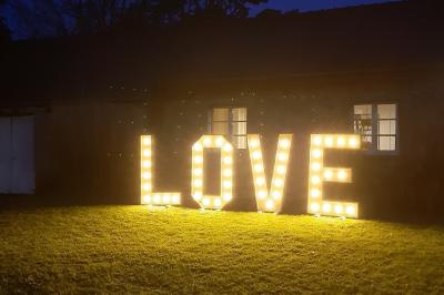 Terrasse en bois avec des chaises noires, adossée à une maison en bardage bois, sous un ciel nuageux.