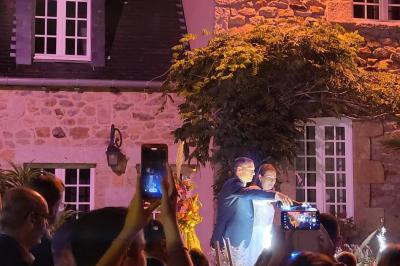 Terrasse en bois avec des chaises noires, adossée à une maison en bardage bois, sous un ciel nuageux.