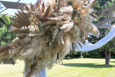 Terrasse en bois avec des chaises noires, adossée à une maison en bardage bois, sous un ciel nuageux.