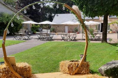 Terrasse en bois avec des chaises noires, adossée à une maison en bardage bois, sous un ciel nuageux.
