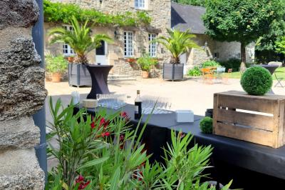 Terrasse en bois avec des chaises noires, adossée à une maison en bardage bois, sous un ciel nuageux.