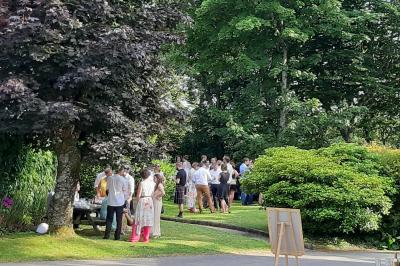 Terrasse en bois avec des chaises noires, adossée à une maison en bardage bois, sous un ciel nuageux.