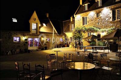 Terrasse en bois avec des chaises noires, adossée à une maison en bardage bois, sous un ciel nuageux.