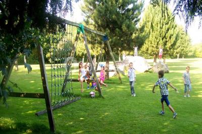 Terrasse en bois avec des chaises noires, adossée à une maison en bardage bois, sous un ciel nuageux.