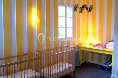 Terrasse en bois avec des chaises noires, adossée à une maison en bardage bois, sous un ciel nuageux.