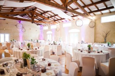 Groupe de personnes réunies en soirée en plein air, avec tables décorées et guirlandes lumineuses suspendues.